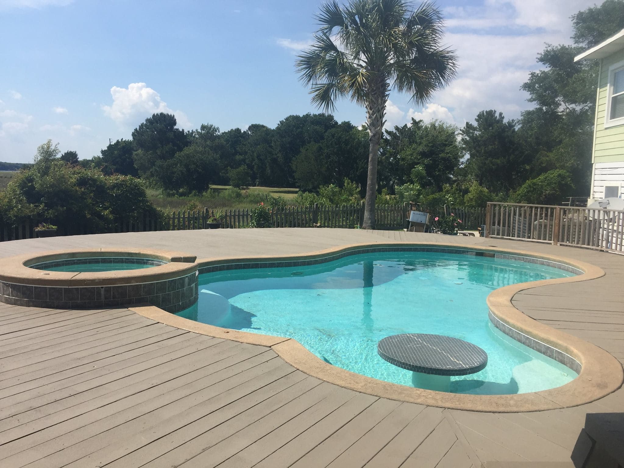 Residential pool deck with a fresh, slip-resistant coating beside a hot tub and palm tree